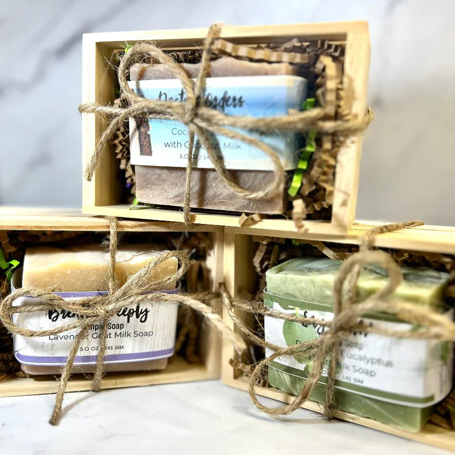 Set of soaps in a wooden crate with twine, featuring various scents.