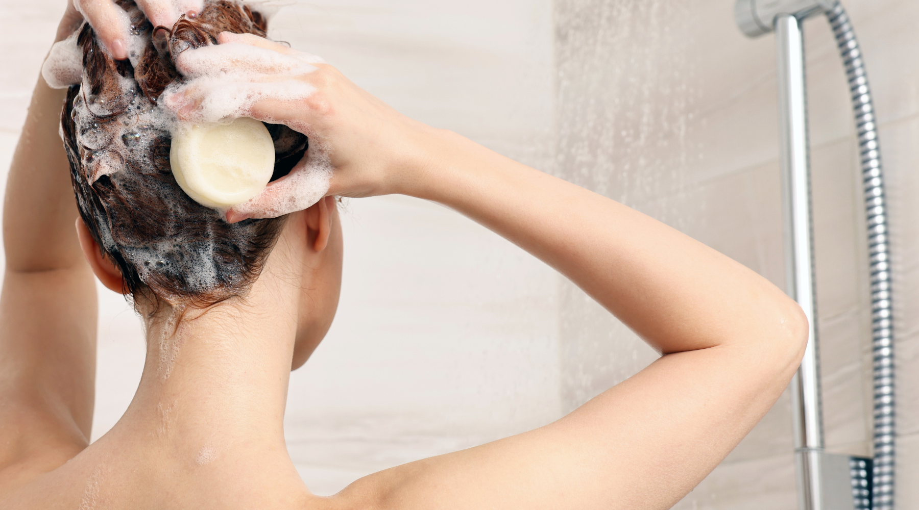 Woman washing hair in shower with shampoo bar