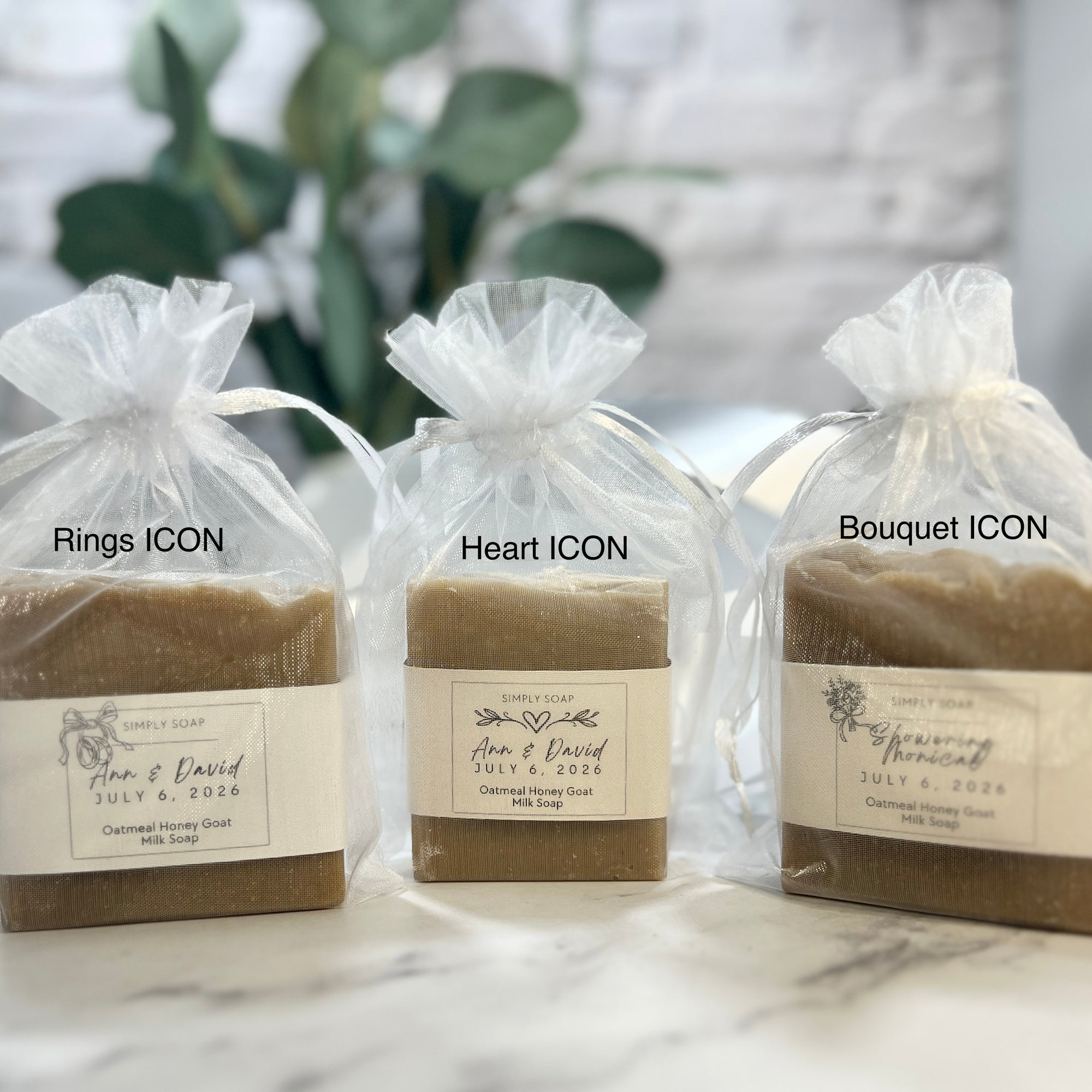 Three bars of soap in clear bags with labels on a marble surface.