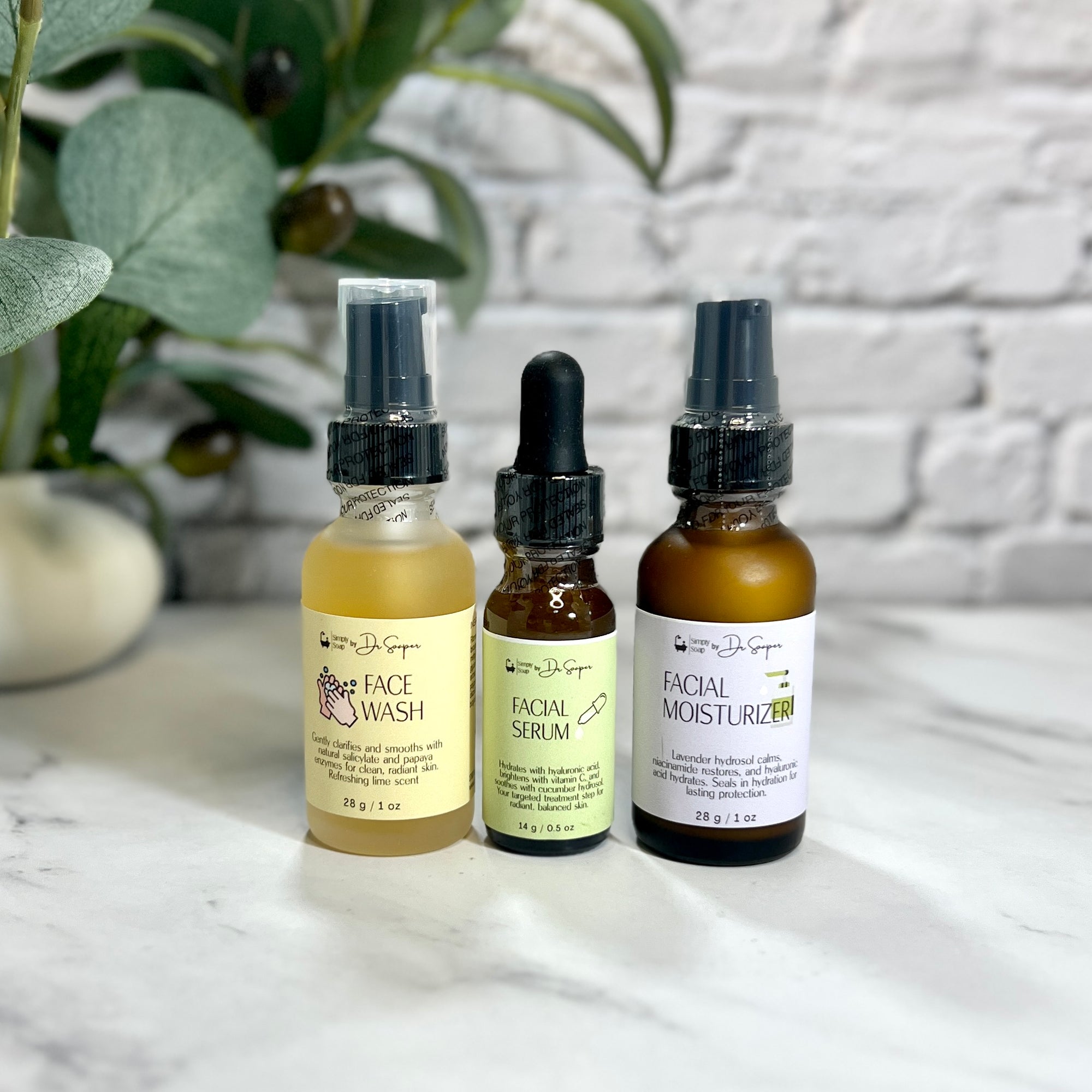 Three skincare products on a marble surface with a plant and textured wall in the background.