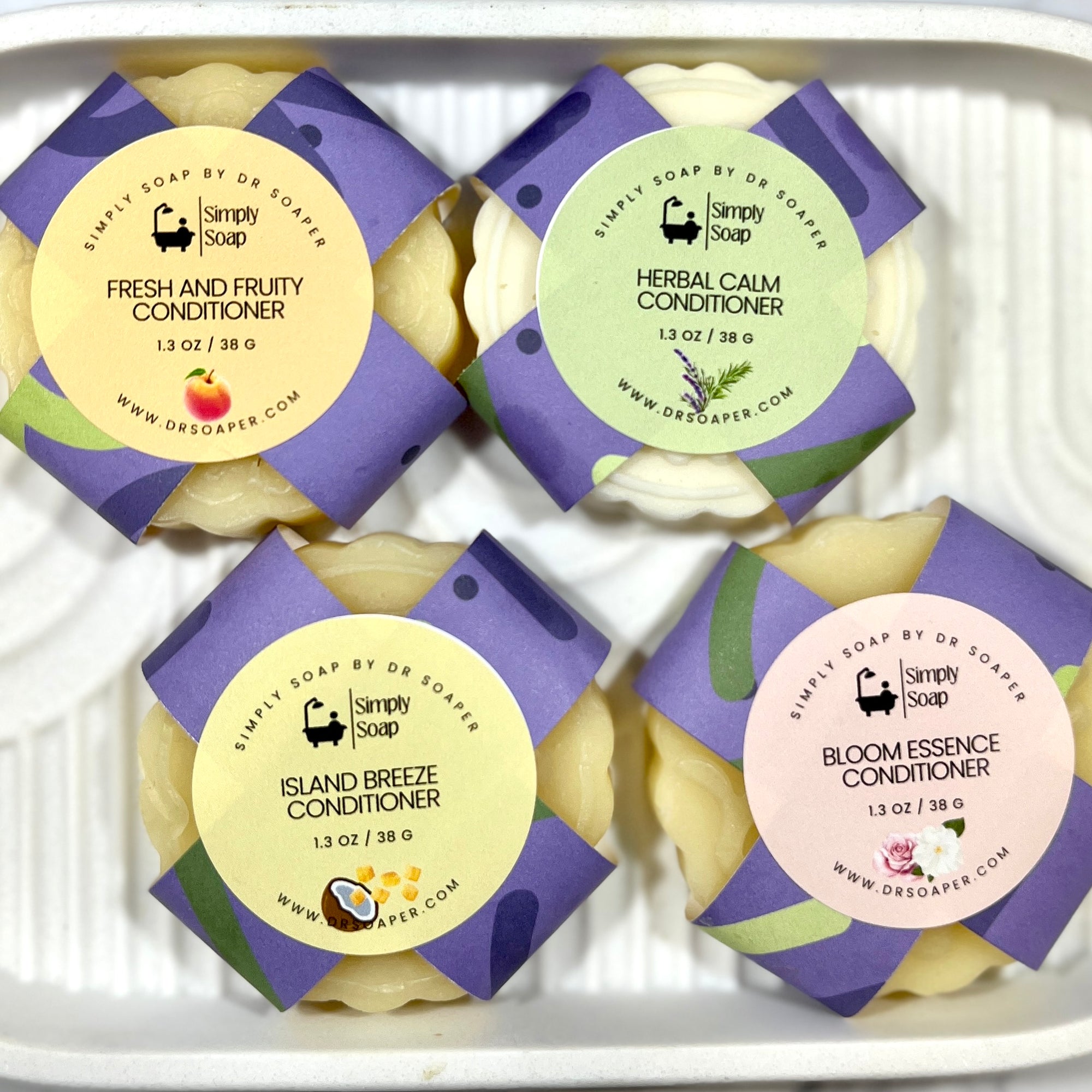 Another view of Four Solid Hair conditioner bars with different scents on a white tray.