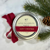 Candle jar labeled 'Apple Bourbon Maple' with a red ribbon and pine branches on a white background