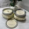Two Apple Vanilla Harvest candles on a marble surface with a plant in the background.