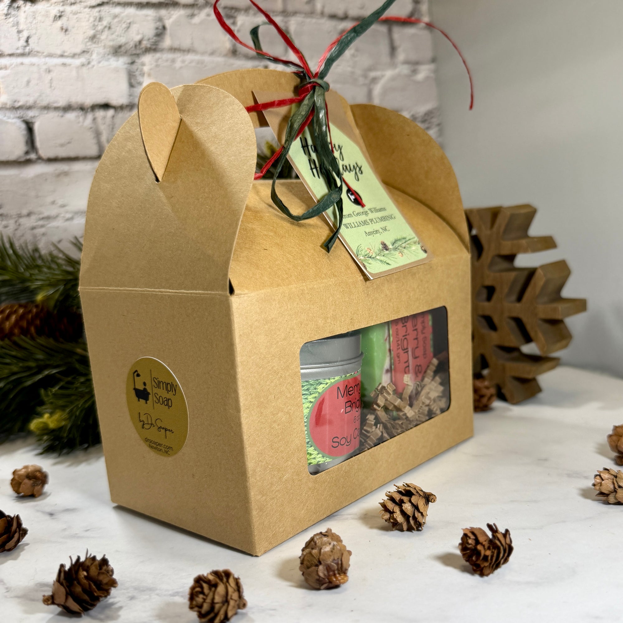A kraft paper gift box with a clear window displaying bar soap and matching candle for Christmas in a Gable Box
