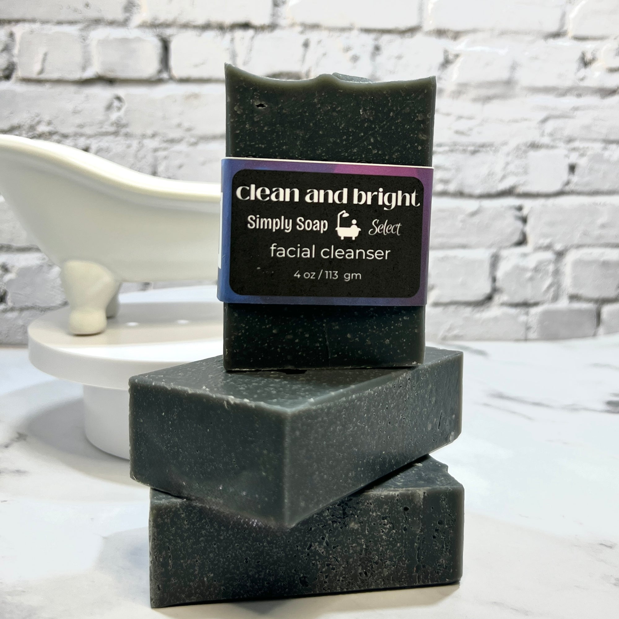 Stack of black soap bars with a label on a white surface and brick wall background
