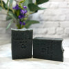Two bars of 'Simply Soap' on a white surface with a blurred background
