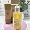 Bottle of face wash with pump dispenser on a white surface, with a cardboard box and decorative elements in the background.
