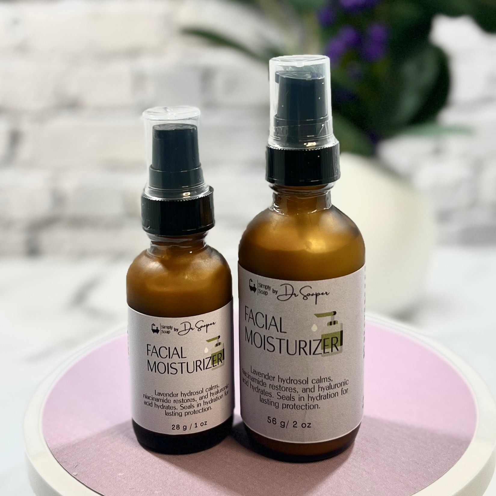 Two bottles of facial moisturizer on a pink coaster with a blurred background