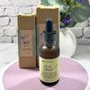 Facial serum bottle with dropper and packaging on a white surface with a brick wall background