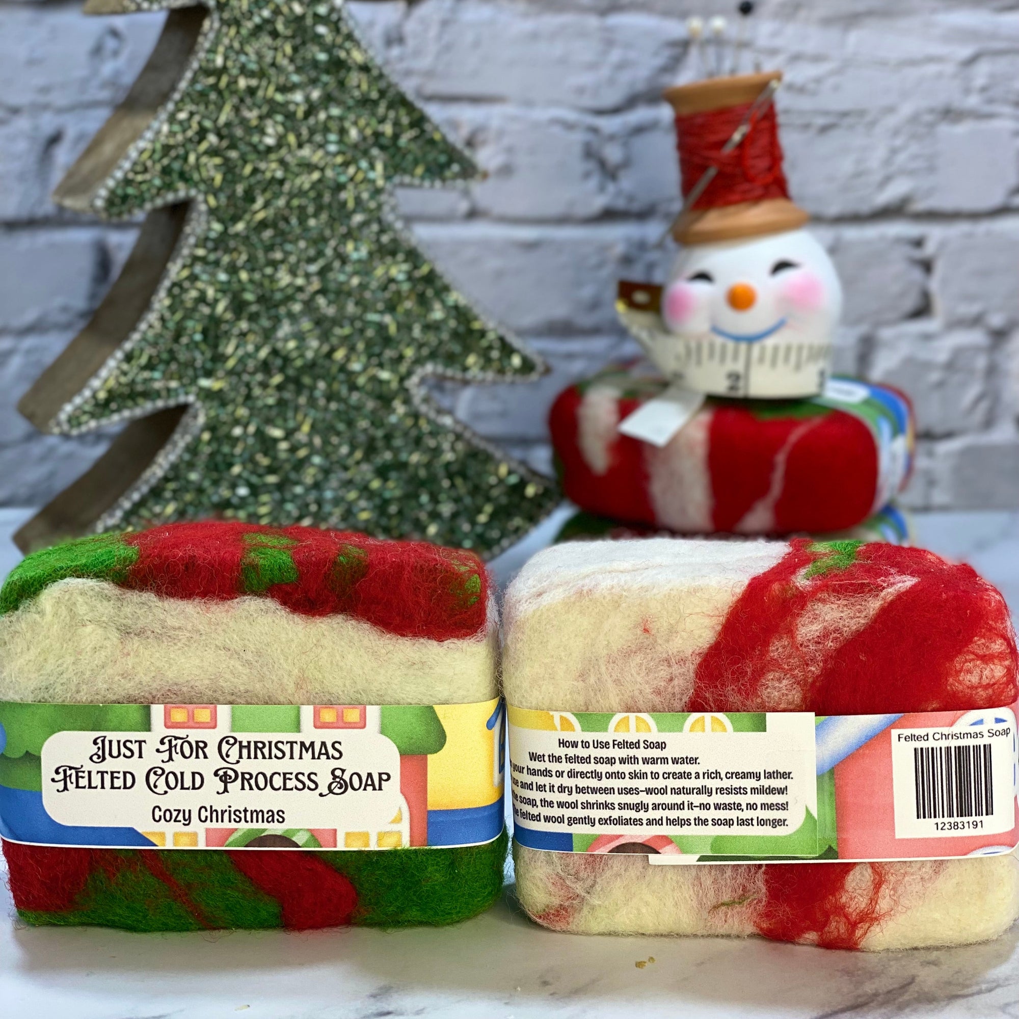 Two soaps with festive designs and a snowman decoration on a marble surface.