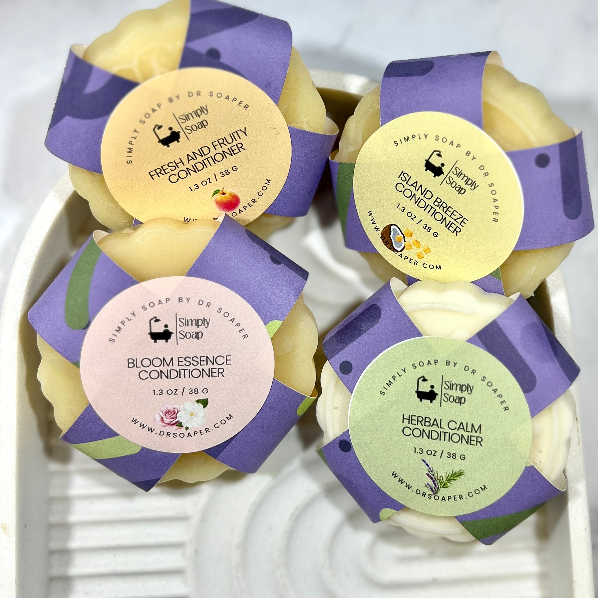 Four solid conditioner bars with purple  labels on a white background