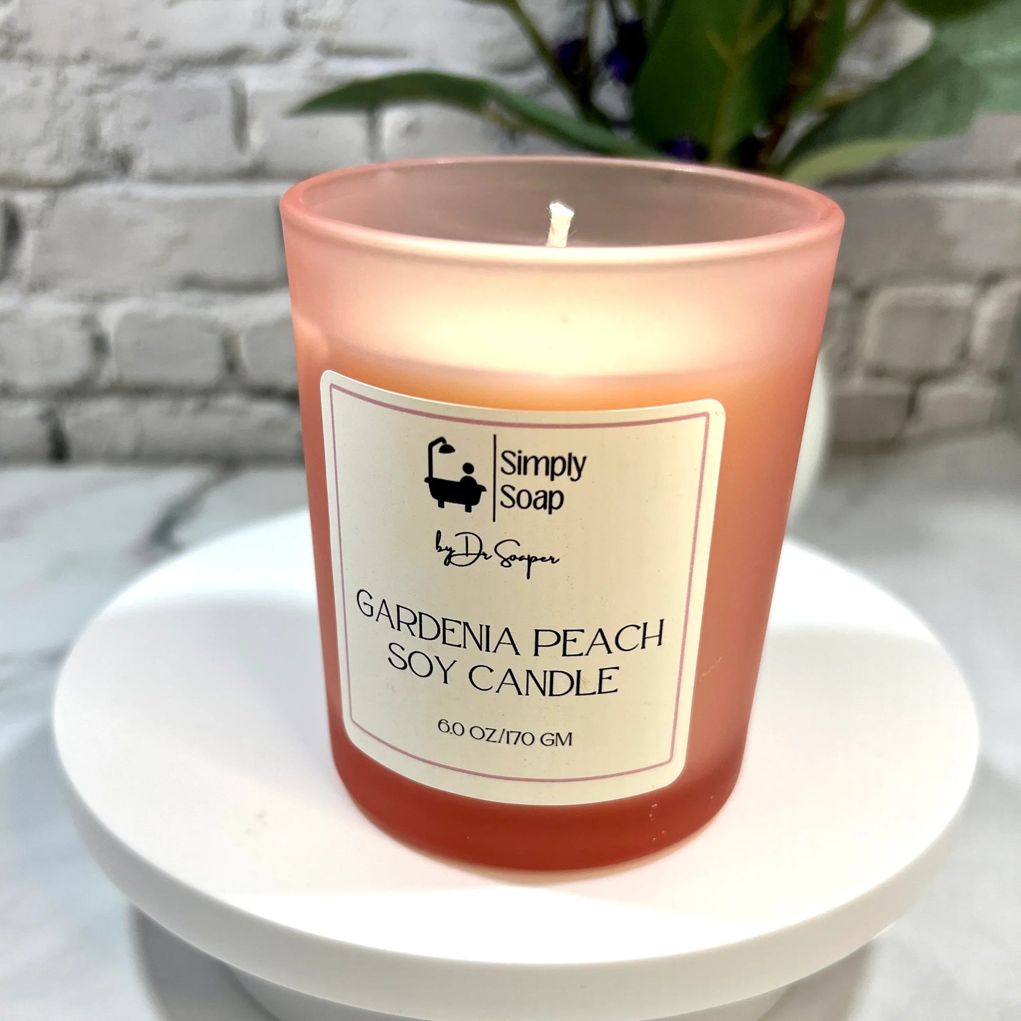 Gardenia Peach soy candle with a 'Simply Soap' label on a white surface.