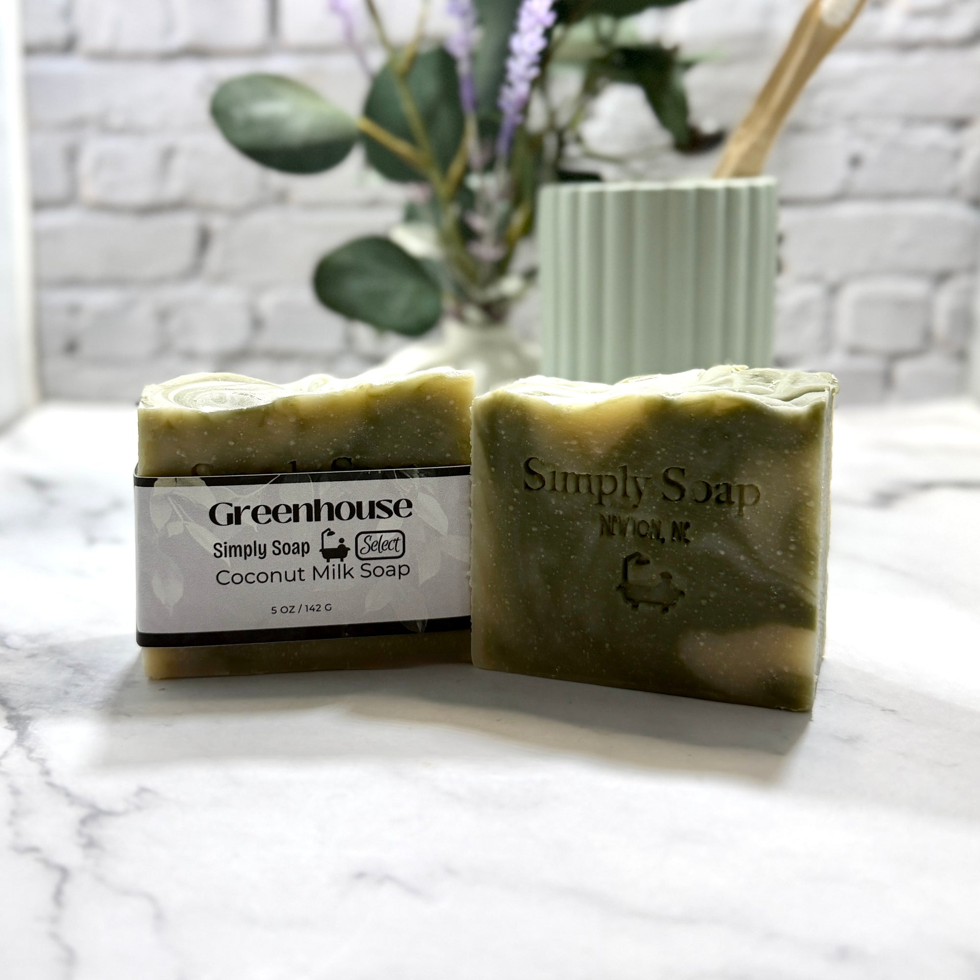 Two bars of soap with 'Greenhouse' and 'Simply Soap' labels on a marble surface.