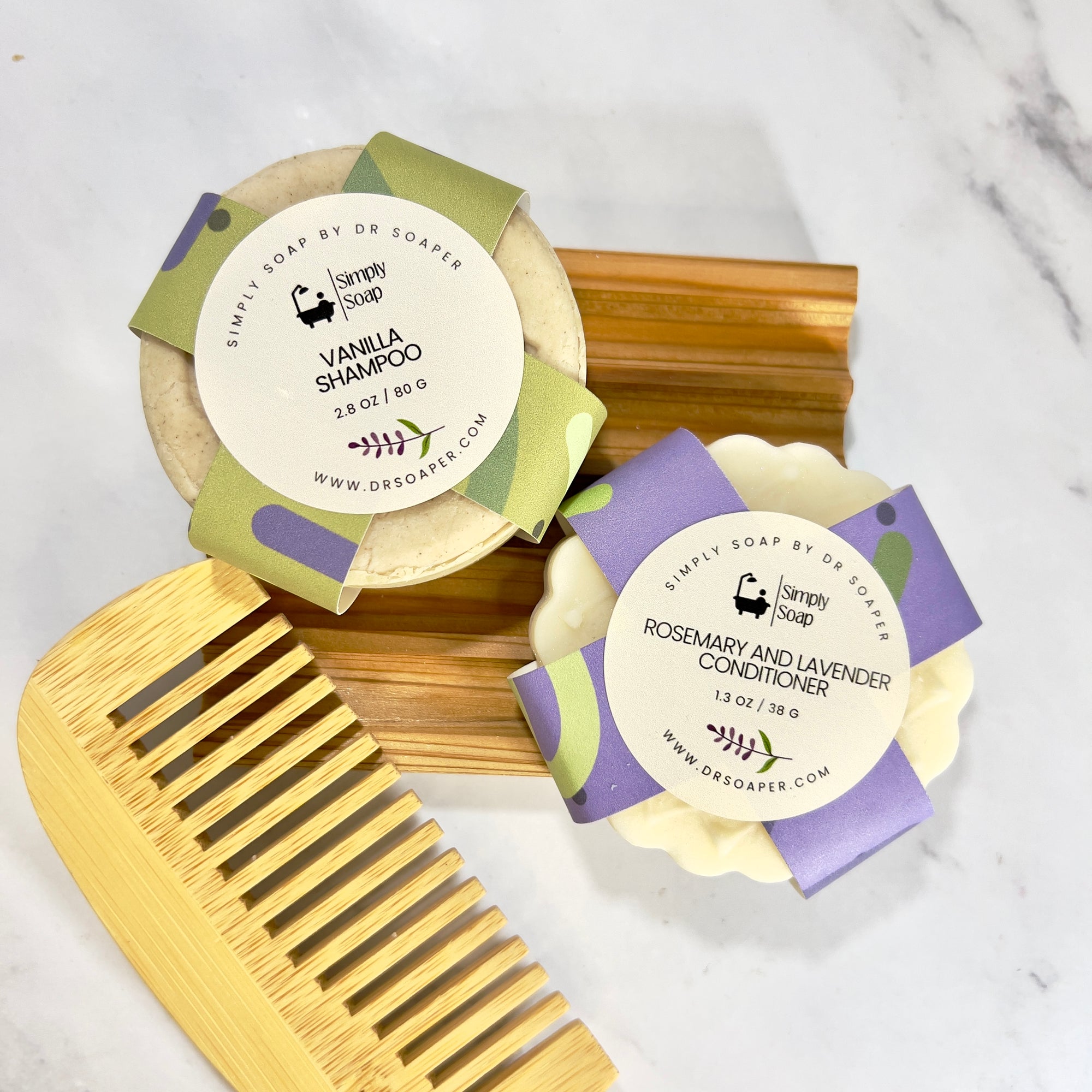 Two hair care  bars with packaging and a wooden comb on a marble surface