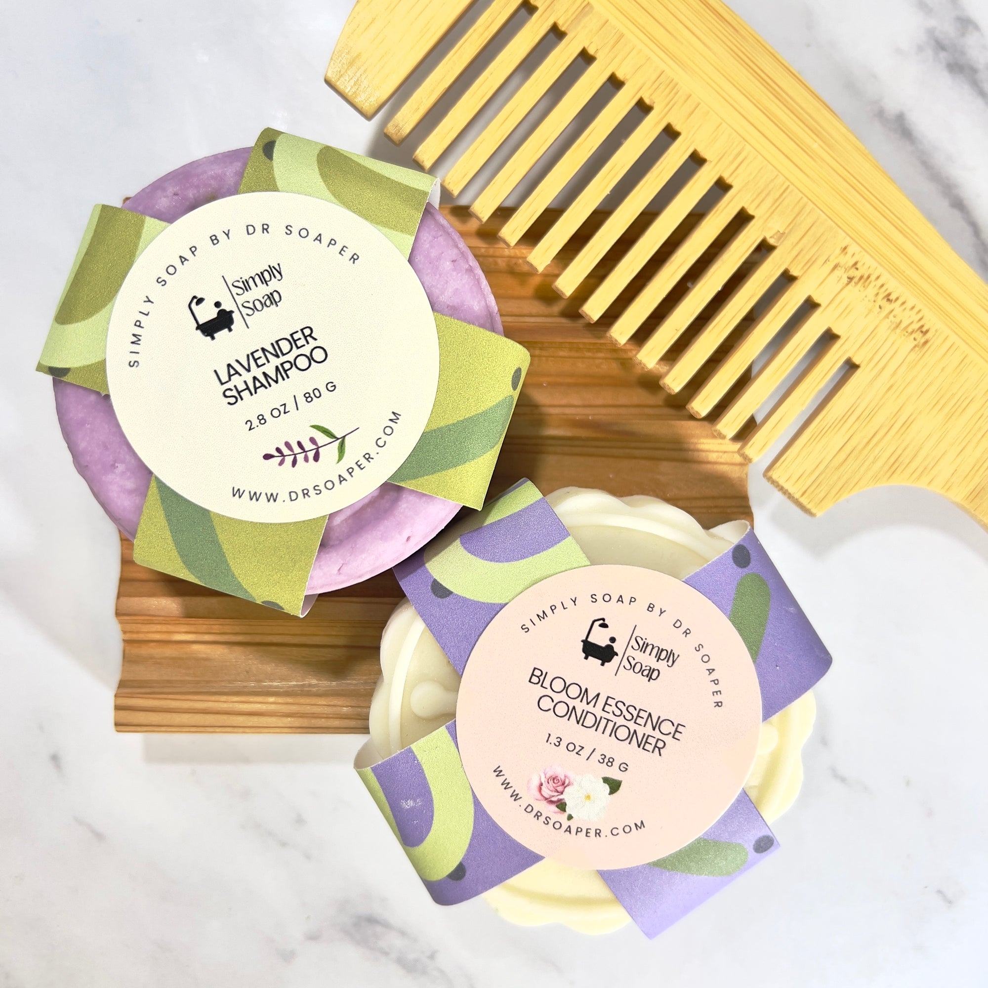 Two hair care bars with labels and a wooden comb on a marble surface