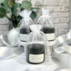 Black candles in clear drawstring bags on a marble surface with decorative elements.