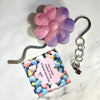 Flower-shaped keychain with a heart-shaped tag on a marble surface
