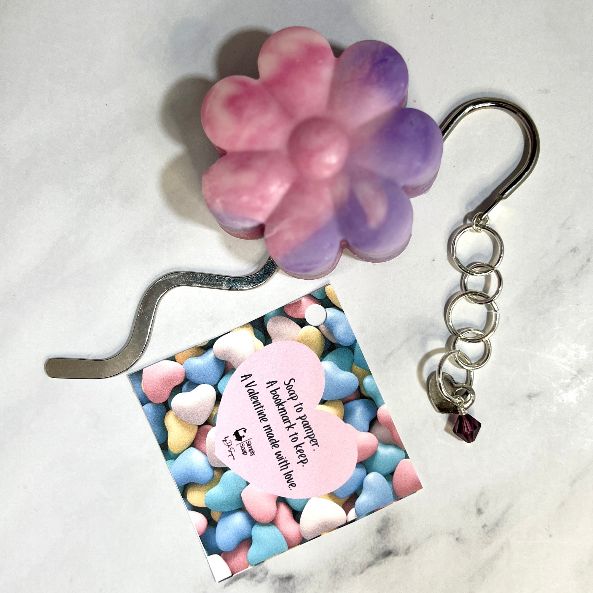 Flower-shaped keychain with a heart-shaped tag on a marble surface