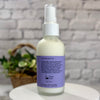 Skincare bottle with a purple label on a white surface against a gray textured wall.