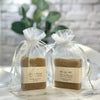 Two bars of soap in clear gift bags with personalized labels on a marble surface.