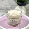 Jar of open lavender hand cream on a pink cloth with a blurred background