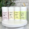 FourSimply Natural Deodorant containers on a white stand with a blurred background