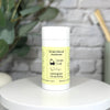 Simply Natural deodorant stick on a white surface with a plant in the background
