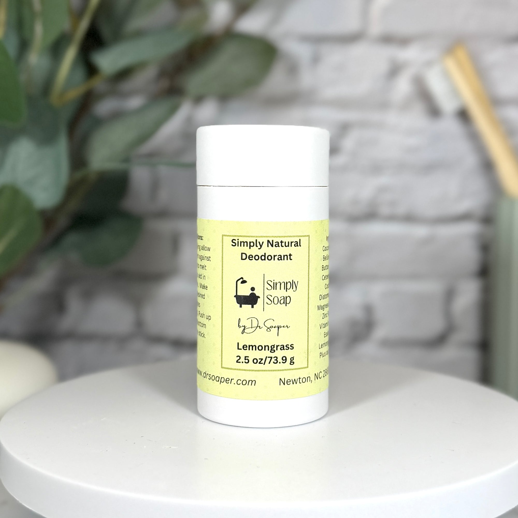 Simply Natural deodorant stick on a white surface with a plant in the background