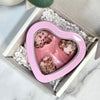 Heart-shaped pink soap mold with white soap bars inside, placed in a box on a marble surface.