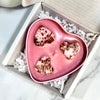 Heart-shaped pink chocolate with white filling and red berries in a box on a marble surface