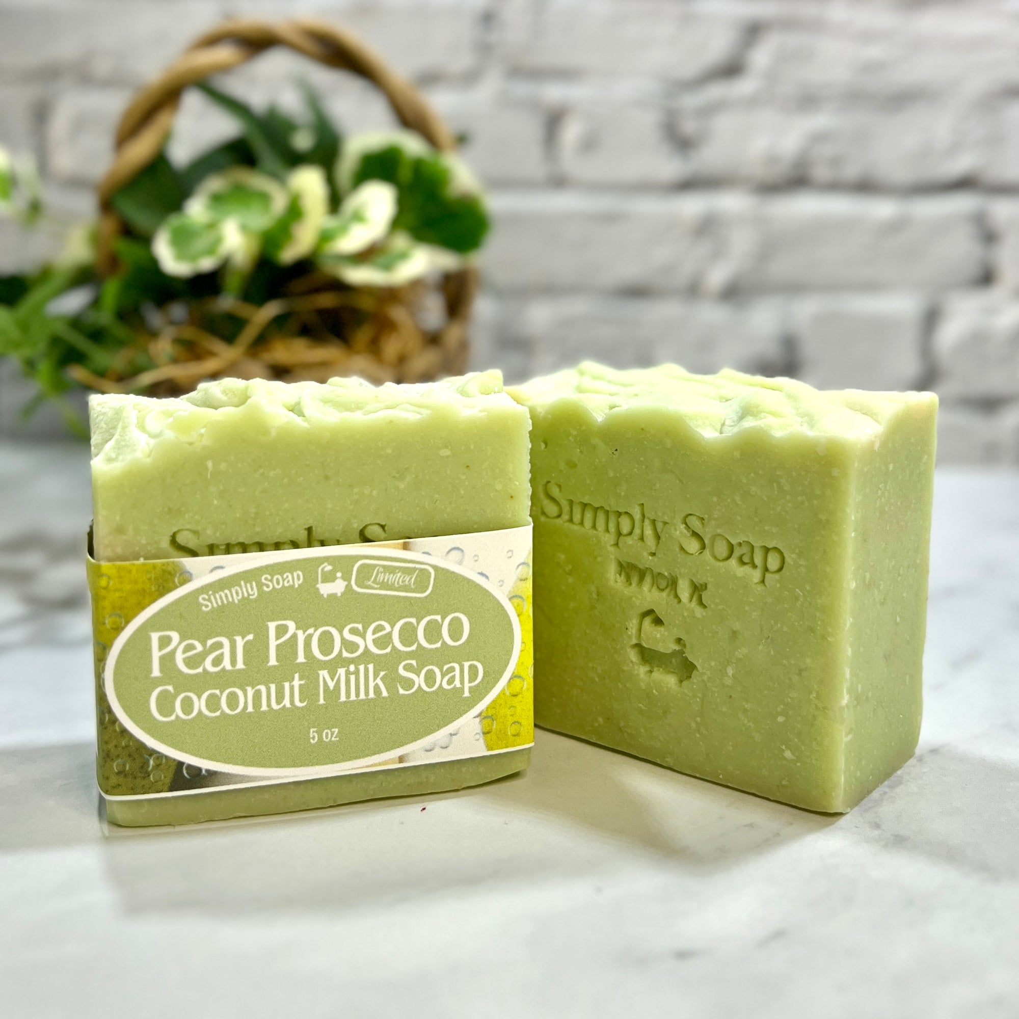 Green soap bar with packaging labeled 'Pear Prosecco Coconut Milk Soap' on a marble surface.