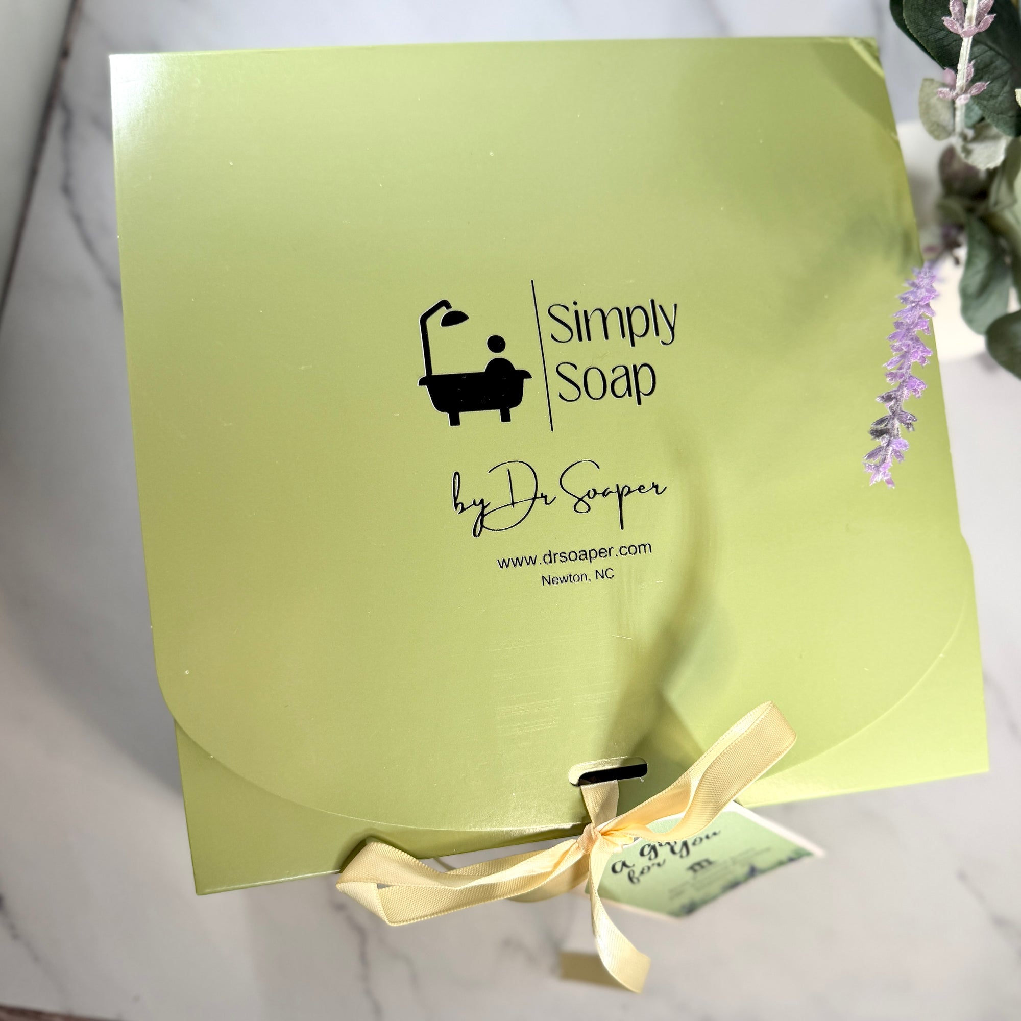A square light green soap gift box from Simply Soap by Dr. Soaper, tied with a  ribbon and small tag
