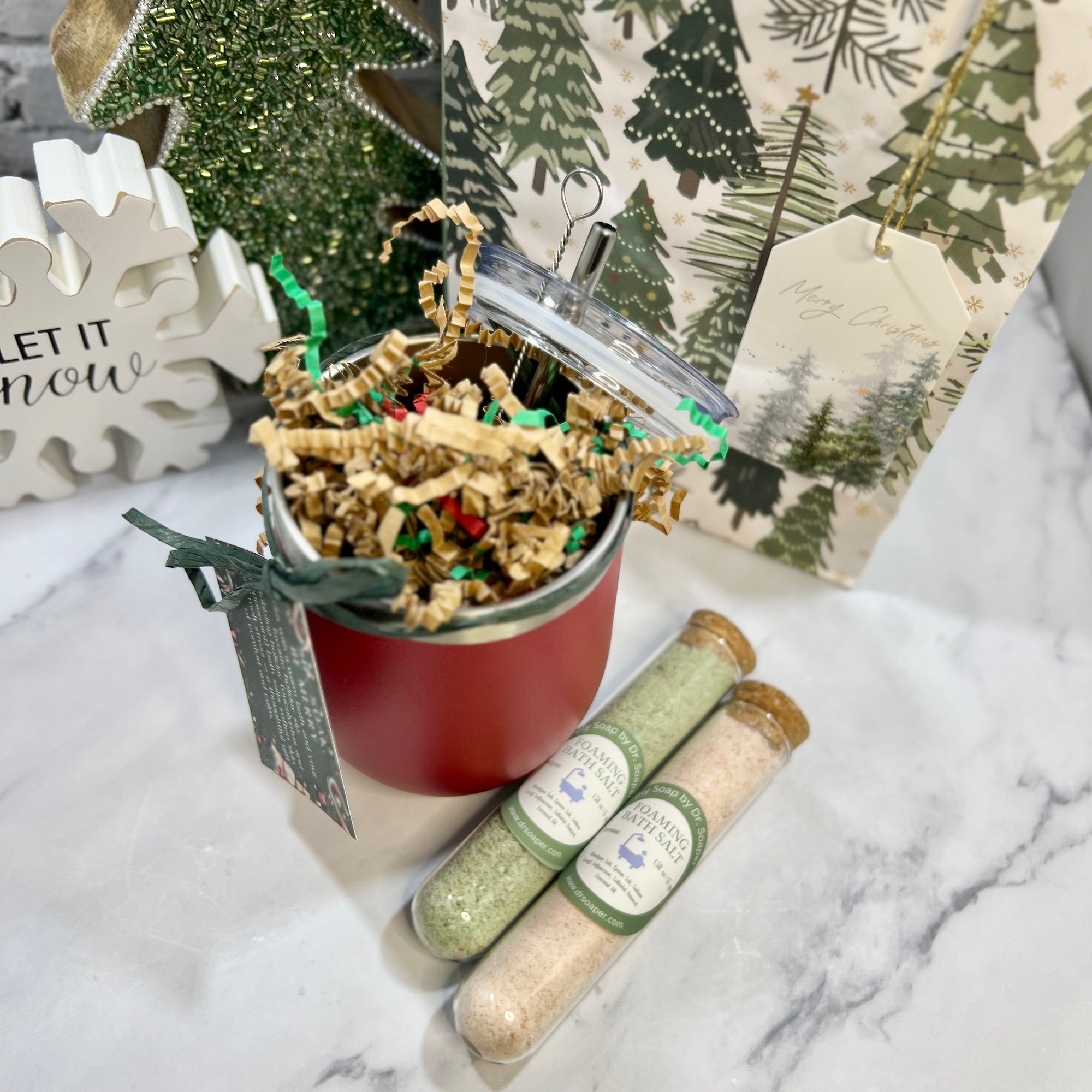 Red Stainless Steel wine tumbler  with straw and brush. Lid askew and bath salts on counter