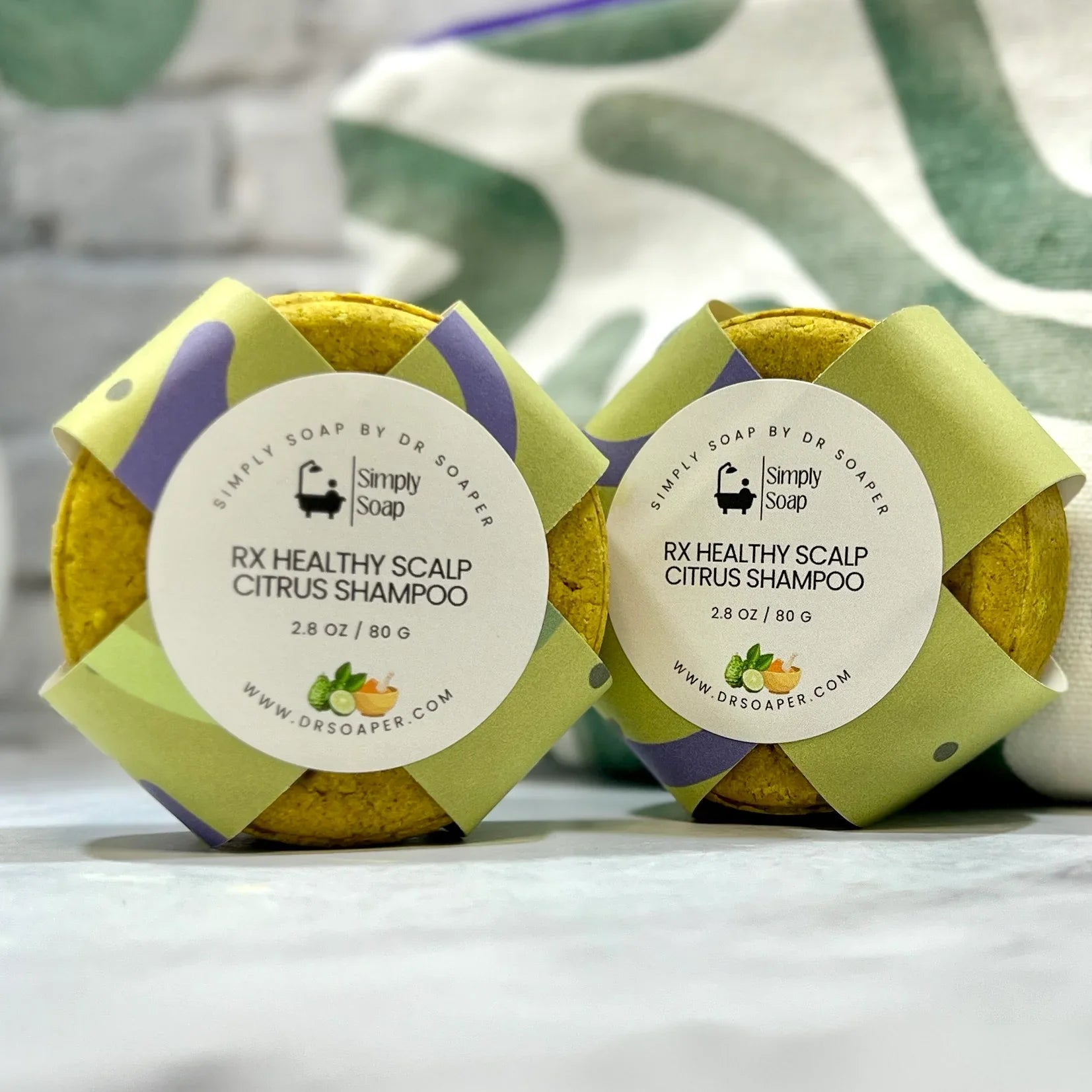 Two packages of RX Healthy Scalp Citrus Shampoo by Simply Soap on a white surface with a green leafy background.