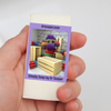 A hand holding a small rectangular cream-colored soap bar purple label and SUDZ with crates