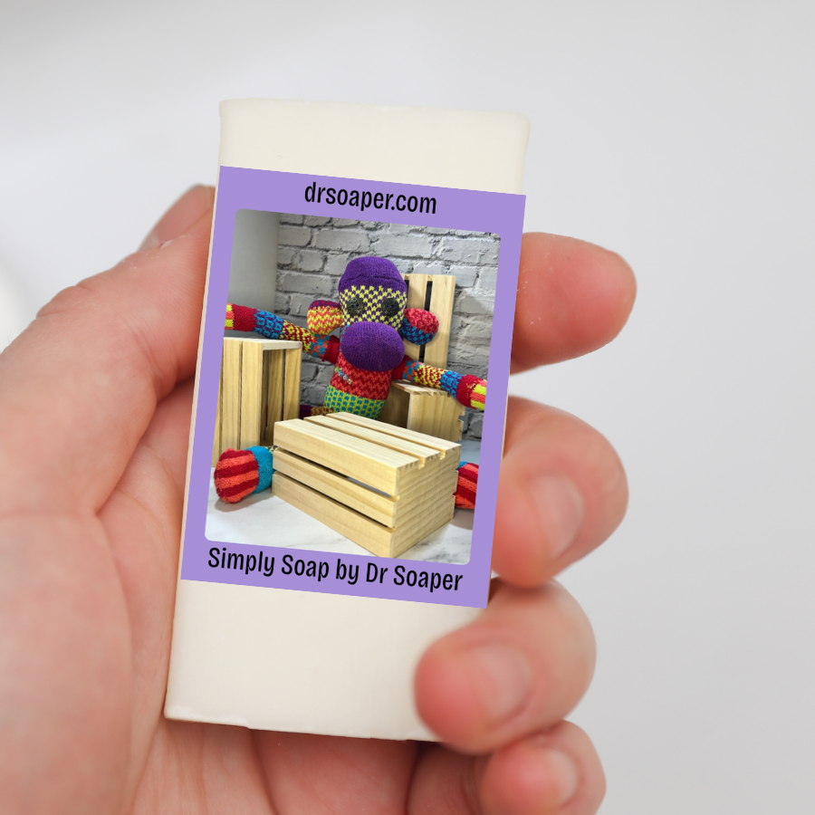 A hand holding a small rectangular cream-colored soap bar purple label and SUDZ with crates