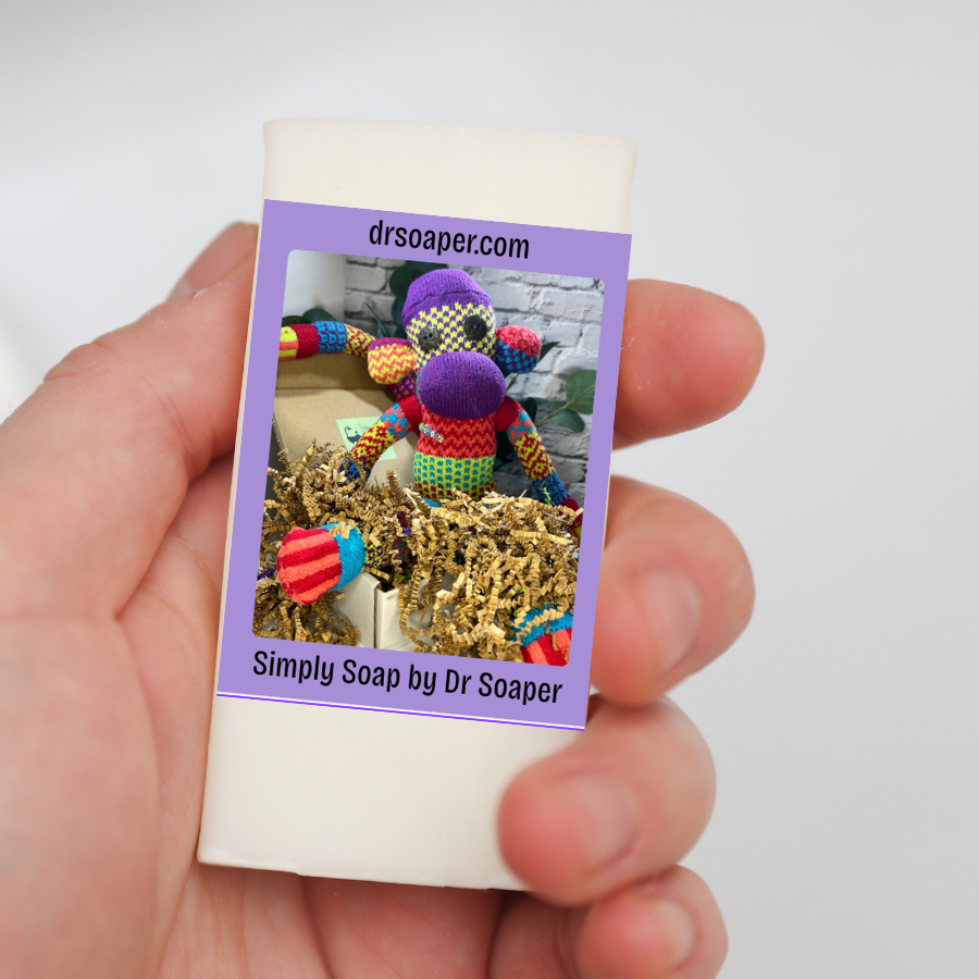 A hand holding a bar of soap with a purple label and SUDZ in krinkle paper
