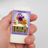 A hand holding a small rectangular soap bar wrapped in purple label with SUDZ testing products.