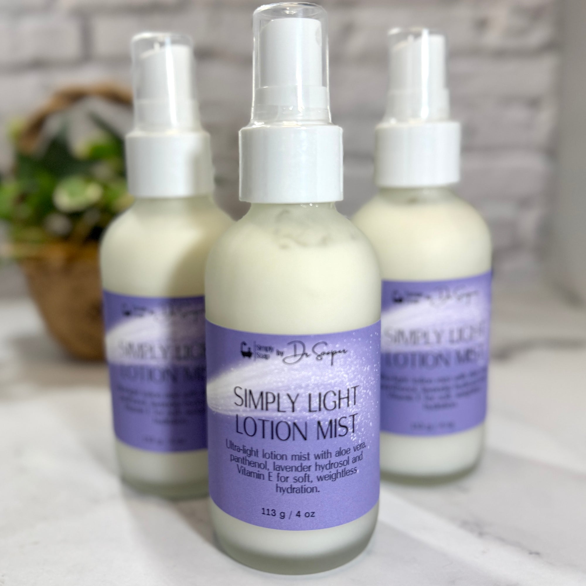 Three bottles of Simply Light Lotion Mist on a white surface with a blurred background
