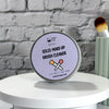 A round metal tin of Dr. Soaper's 'Solid Make-Up Brush Cleaner' displayed on a white round pedestal against a gray brick wall background.