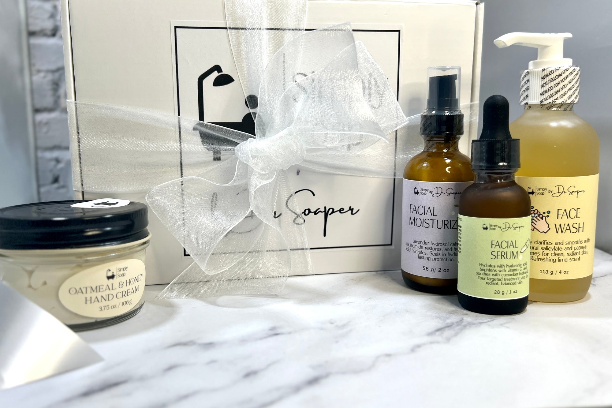 Set of skincare products including bottles and a jar on a marble surface with a branded box in the background.