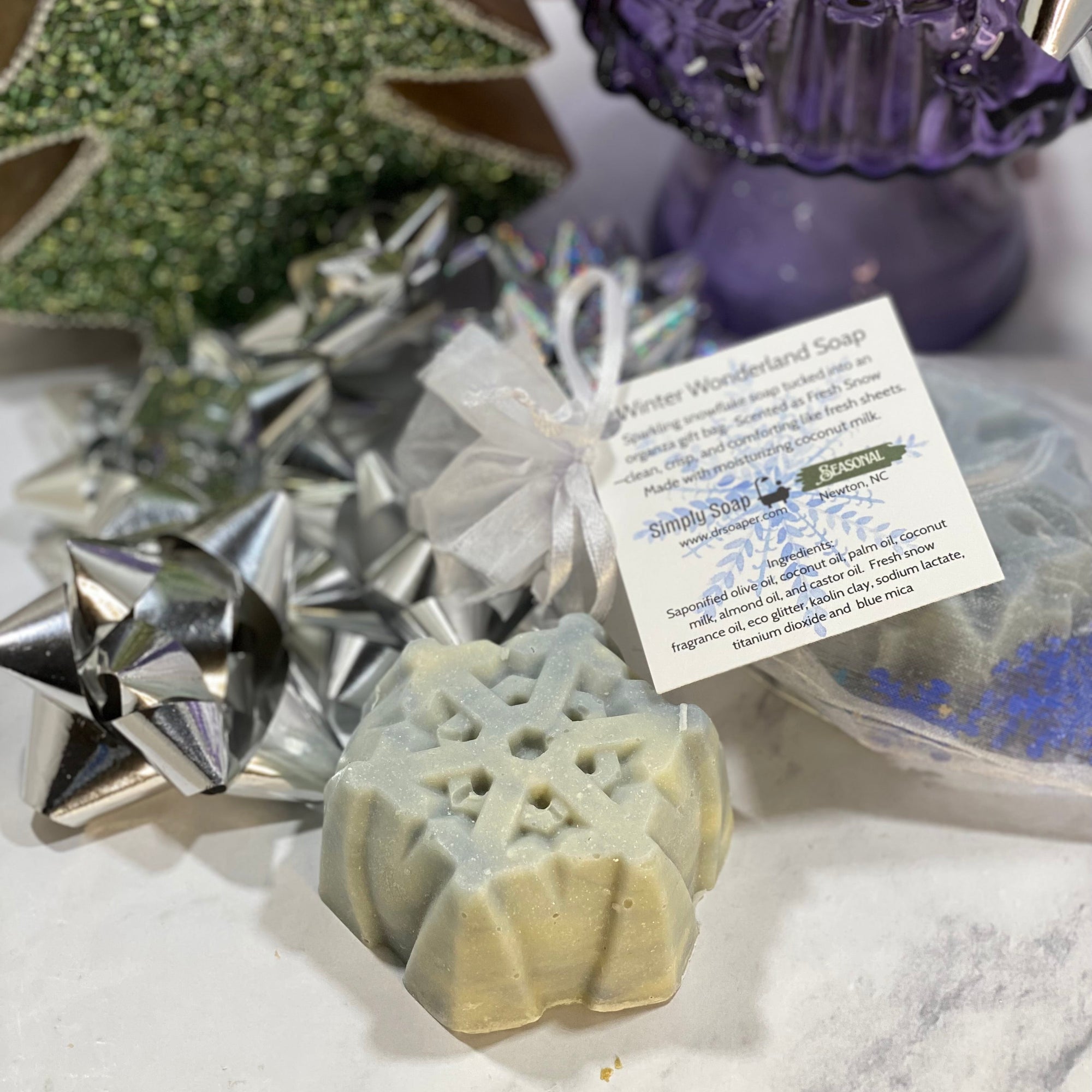 Decorative soap with a snowflake design, surrounded by festive decorations on a white surface.