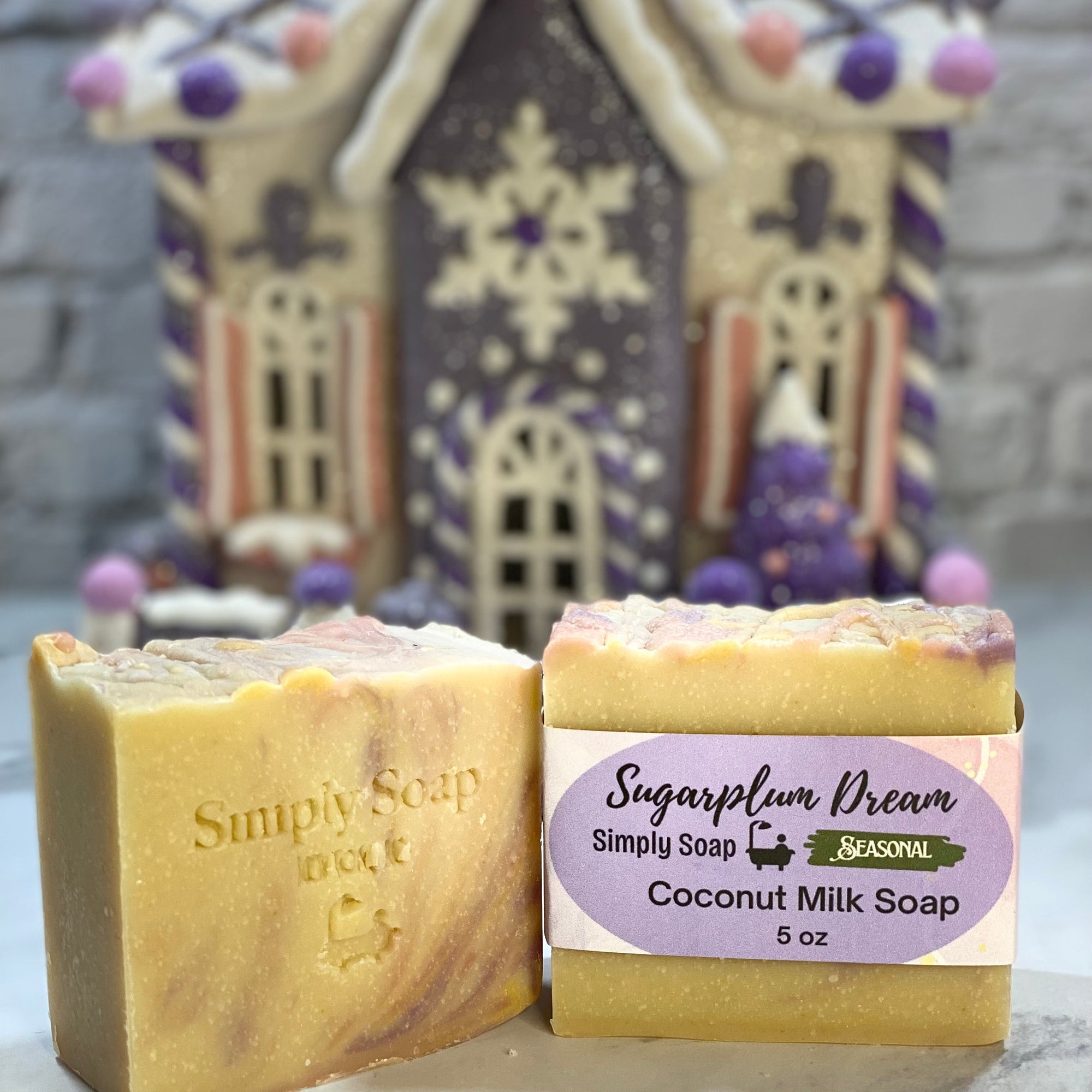 Two bars of soap with a decorative gingerbread house in the background