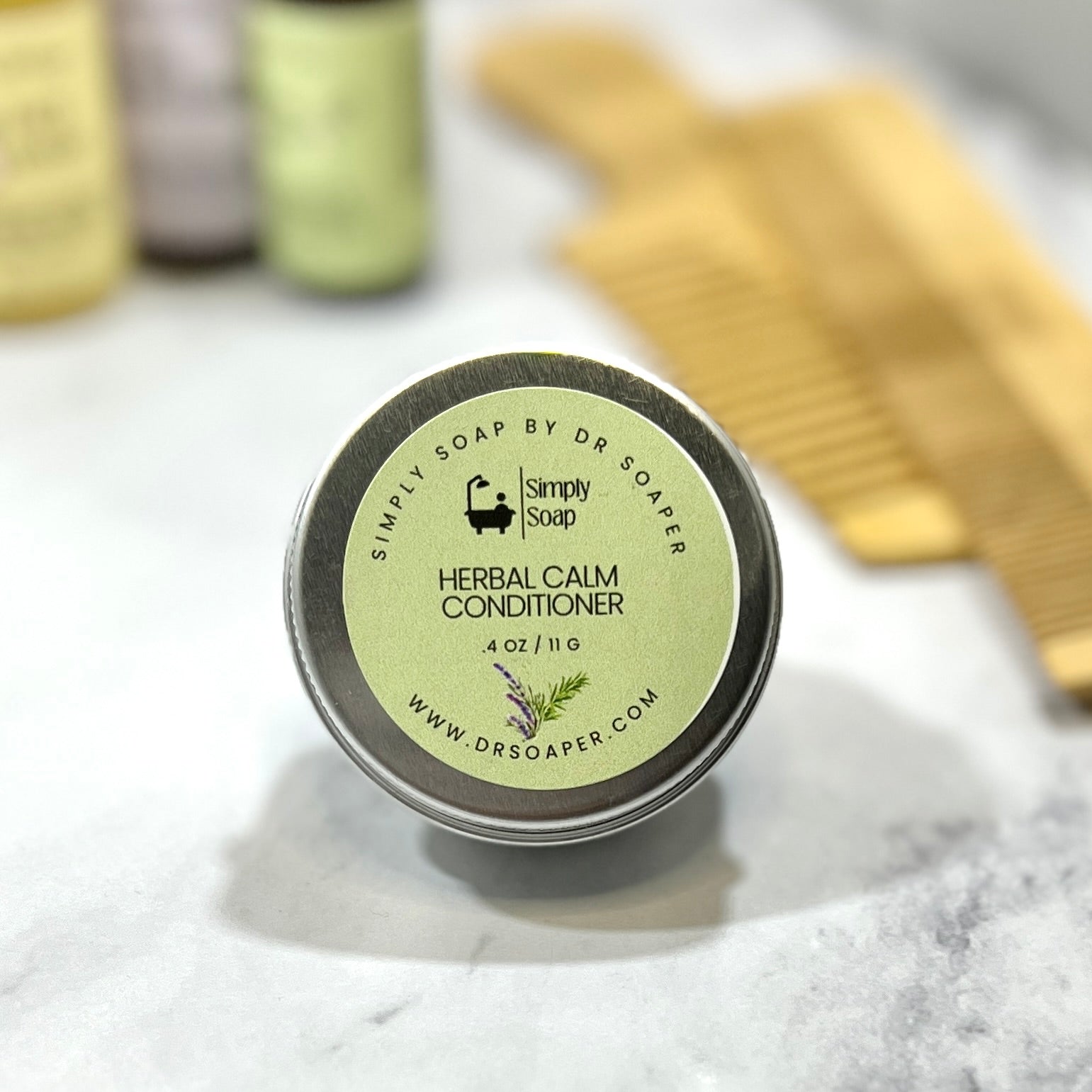 Tin of Simply Soap Herbal Calm Conditioner on a white surface with a comb in the background.