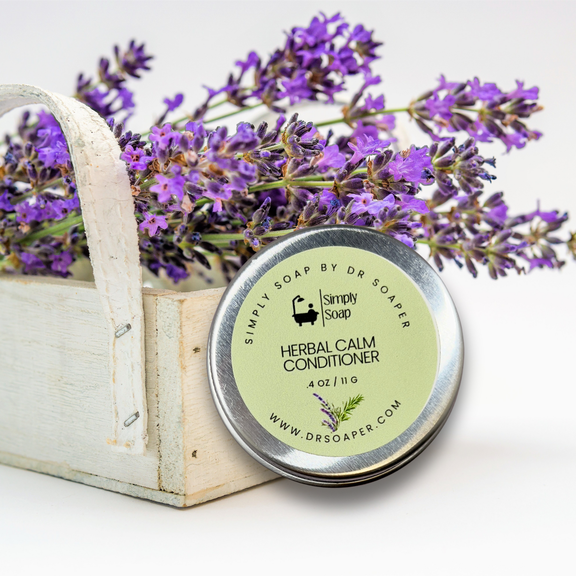 Travel tin of Herbal Calm Conditioner' with lavender flowers in a wooden basket.