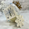 Gift bag with a snowflake ornament and tag on a textured surface