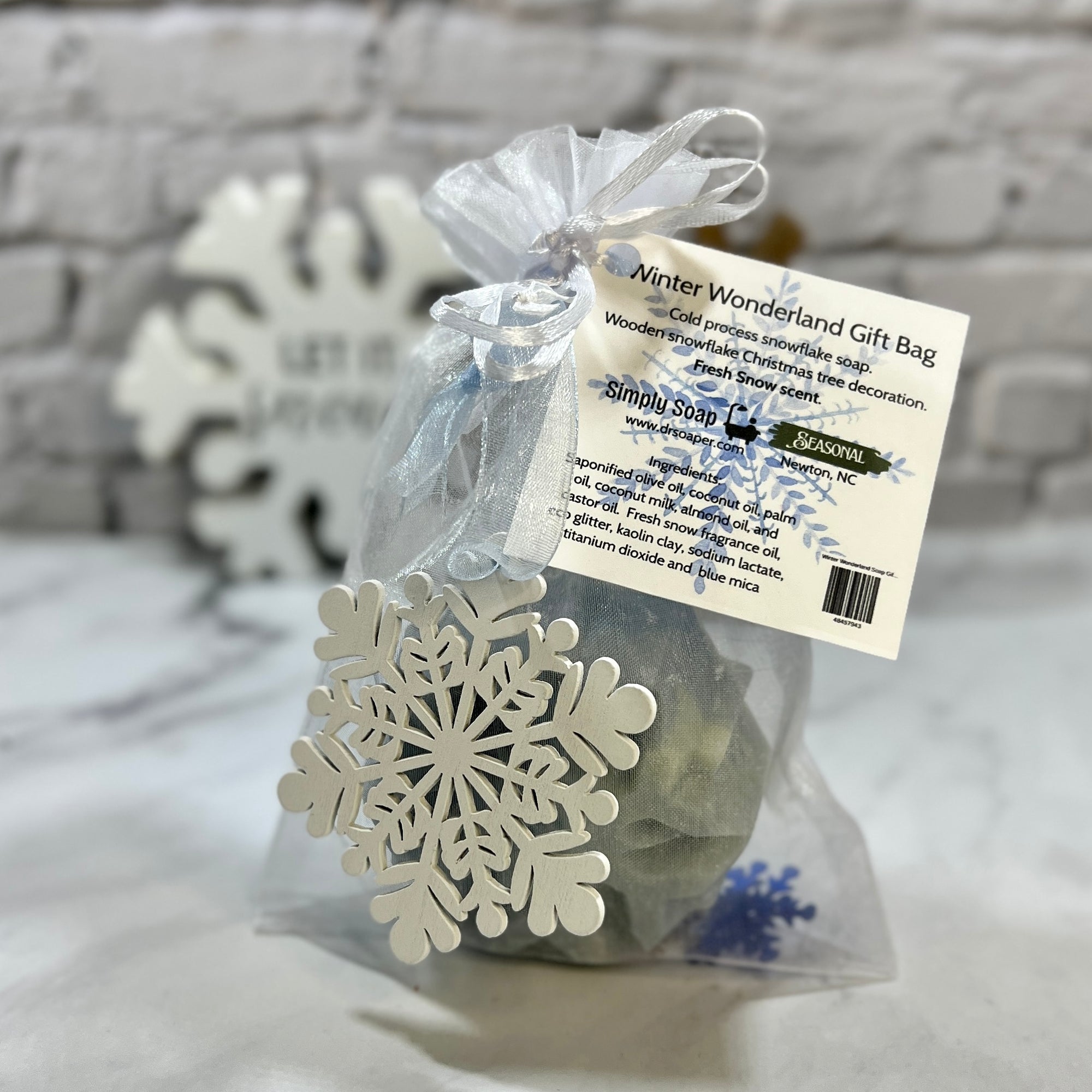 Wooden snowflake ornament in a clear gift bag with a label on a textured surface.