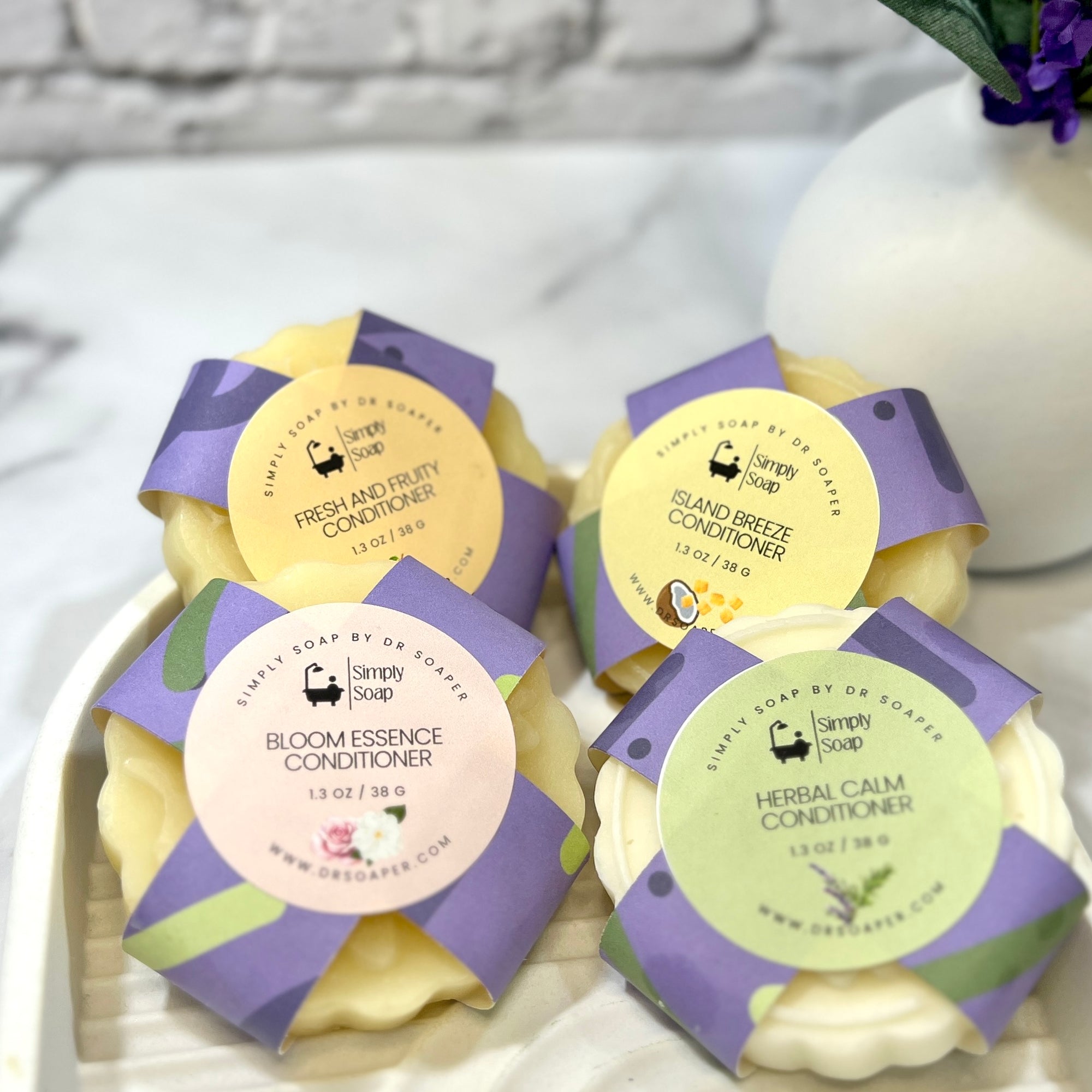 Four solid hair conditioner bars with purple packaging and labels on a white surface.
